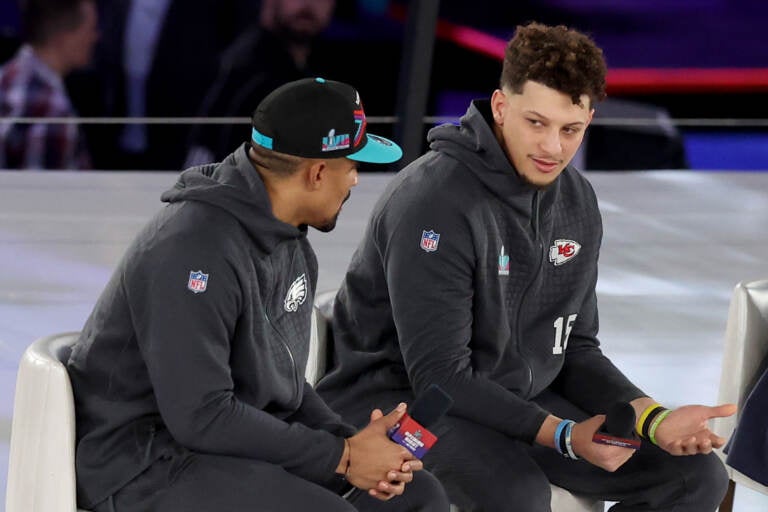 Mahomes and Hurts sit side by side onstage.