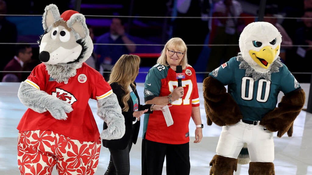 Donna Kelce stands between the two mascots for her sons' teams.