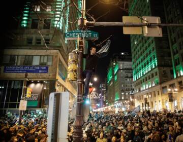A man climbs a traffic pole as Philadelphia Eagles fans celebrate victory in Super Bowl LII against the New England Patriots on February 4, 2018 in Philadelphia