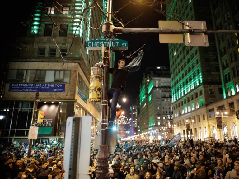 A man climbs a traffic pole as Philadelphia Eagles fans celebrate victory in Super Bowl LII against the New England Patriots on February 4, 2018 in Philadelphia