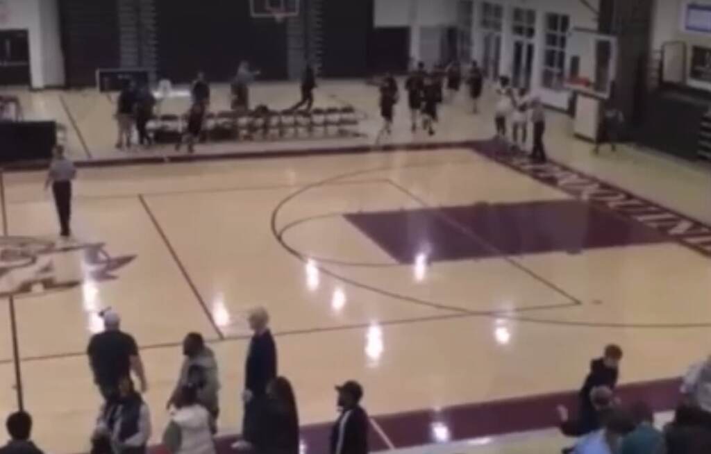 An aerial view of people running from a basketball court.