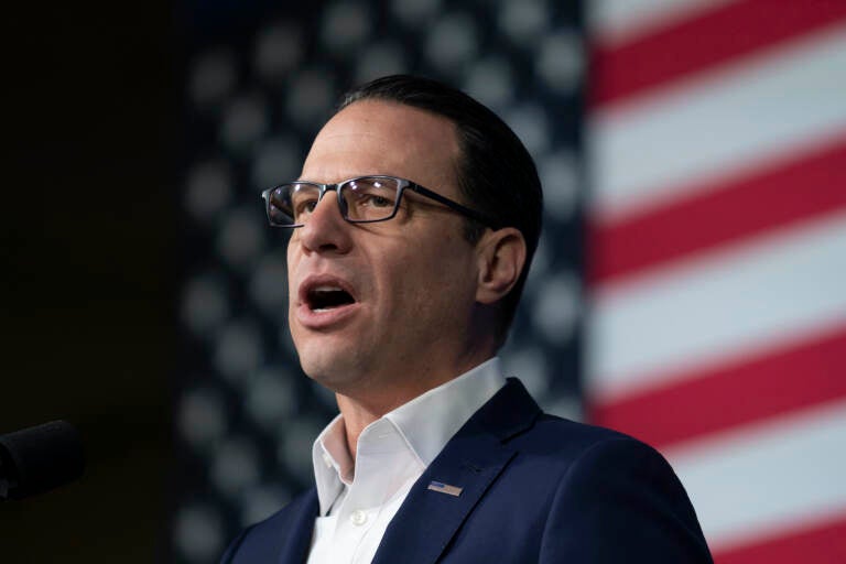 A close-up of Gov. Josh Shapiro speaking. The U.S. flag is visible behind him.