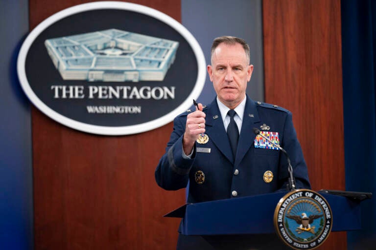 A man in uniform speaks from a podium.