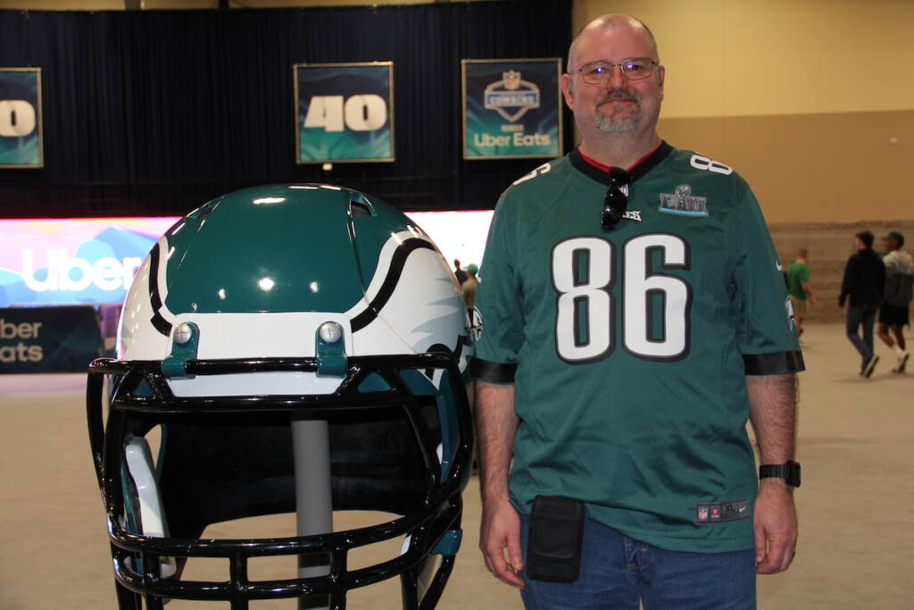 Albert Dixon poses, in an Eagles jersey, next to a giant Eagles helmet replica.