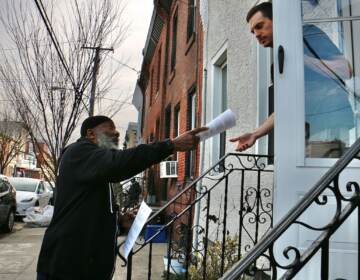 A person passes out a brochure to someone in a house.