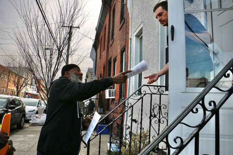 A person passes out a brochure to someone in a house.