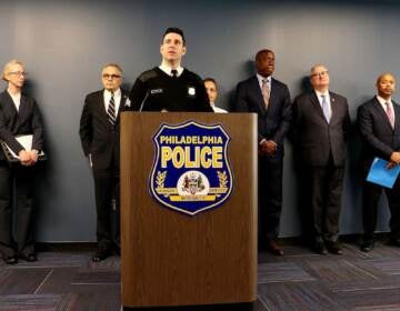 A group of people stand behind a podium with a sign that reads Philadelphia Police.