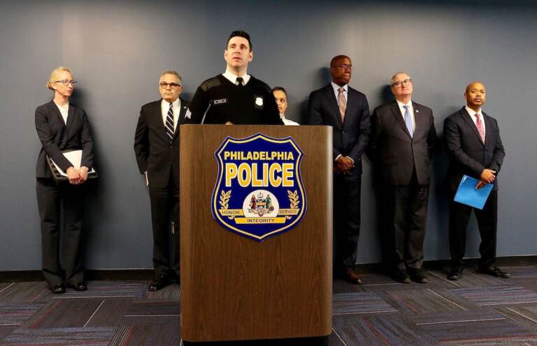 A group of people stand behind a podium with a sign that reads Philadelphia Police.