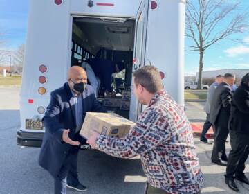 State Rep. Franklin Cooke (left) loads a box of baby formula onto a truck with an unidentified volunteer