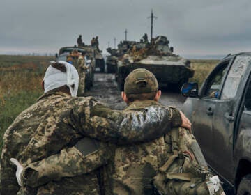 A Ukrainian soldier helps a wounded comrade on the road in reclaimed territory in the Kharkiv region