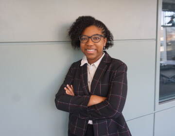 Cayla Waddington leans against a wall, smiling as she poses for a photo.