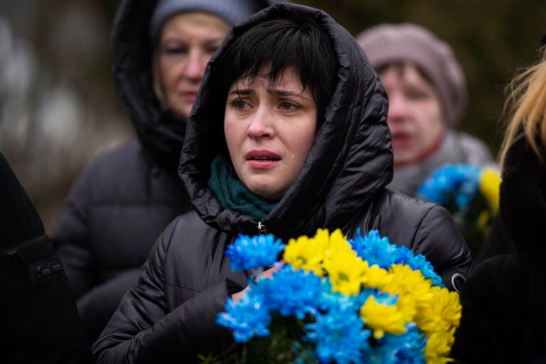 A woman crying and holding flowers