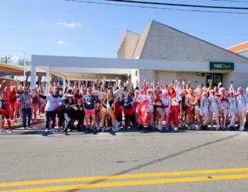 A group of people wearing red pose for a photo on a street.