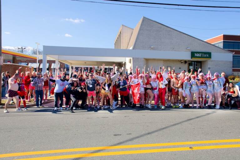 A group of people wearing red pose for a photo on a street.