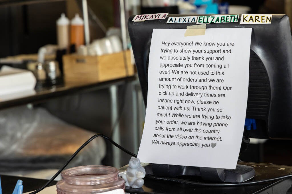 A piece of paper with writing asking for customers' patience is taped to a computer at Amy's Pizzeria.