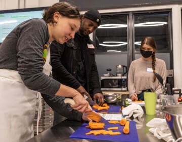 Roshan Basil watches as someone demonstrates how to julienne carrots.