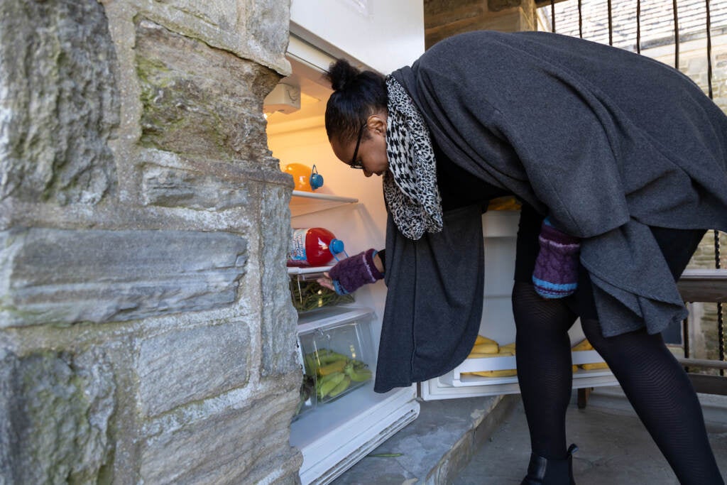 Nicole Williams leans over to place something in the community fridge.