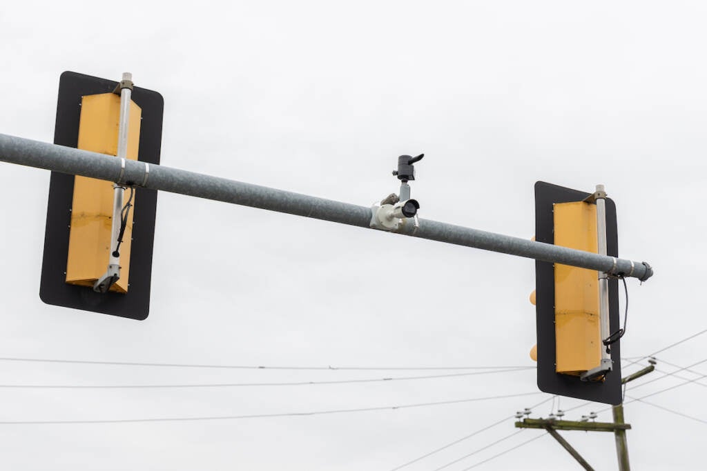 A security camera attached to traffic lights at an intersection is visible.