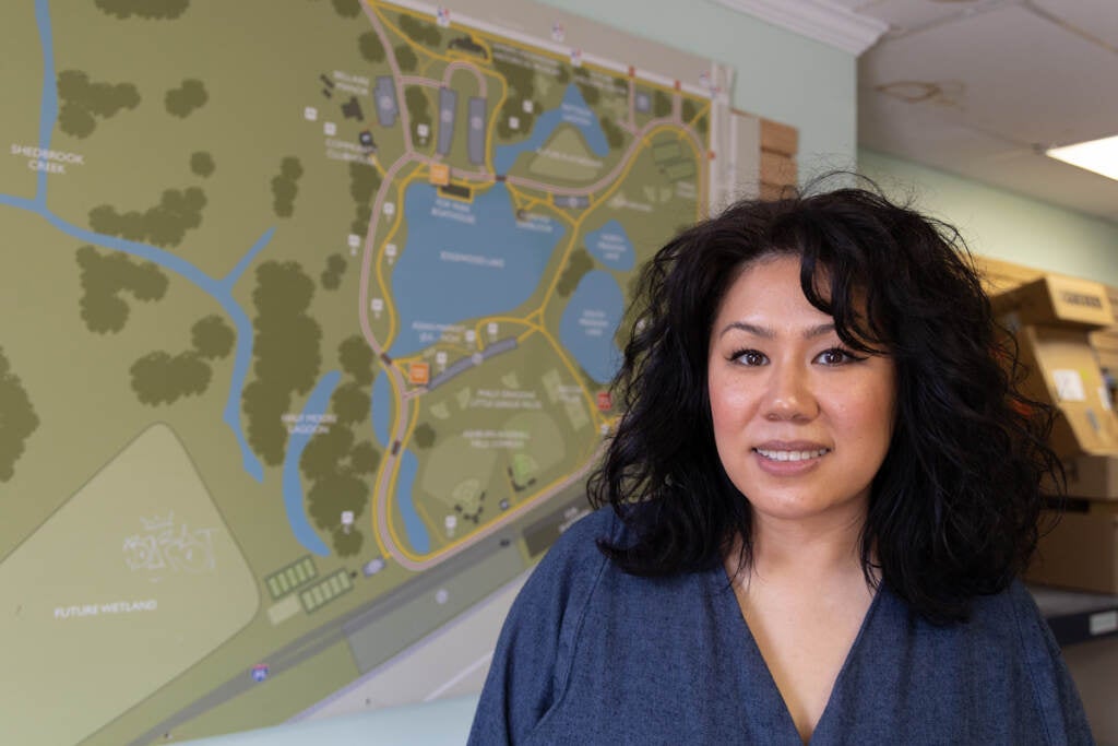 Catzie Vilayphonh poses for a photo in front of a map of FDR Park.