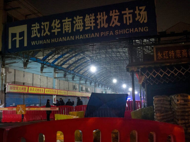 Security guards stand in front of the Huanan Seafood Wholesale Market in Wuhan, China, on Jan. 11, 2020, after the market had been closed following an outbreak of COVID-19 there. Two studies document samples of SARS-CoV-2 from stalls where live animals were sold. (Noel Celis/AFP via Getty Images)