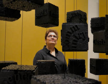 A woman looks at several blocks hanging in the air in the art exhibit.