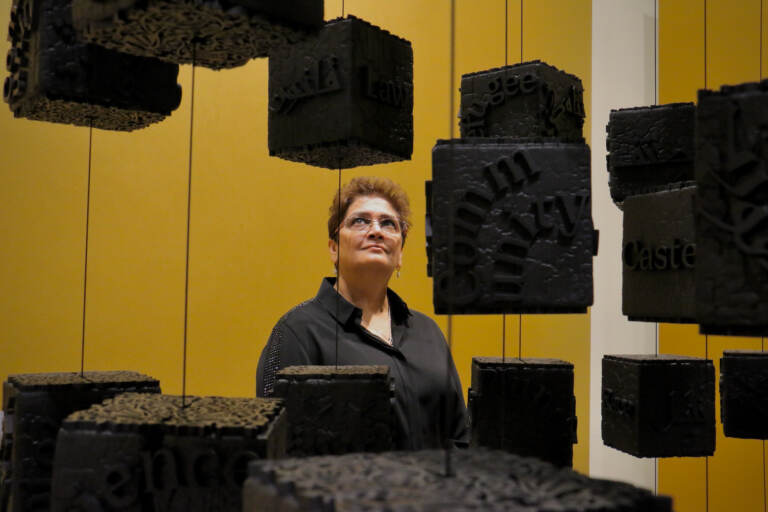 A woman looks at several blocks hanging in the air in the art exhibit.