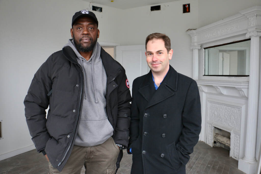Developer and contractor Dawud Bey stands with Philadelphia Accelerator Fund Executive Director David Langlieb in one of the 17 apartments Bey is renovating