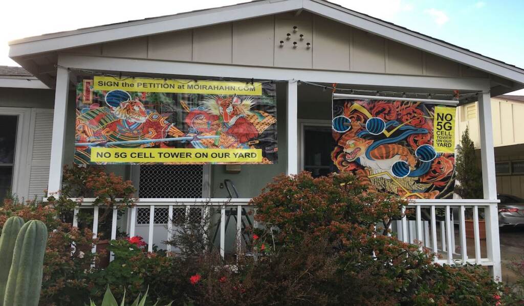 The front porch of Moria Hahn and Mark Hotchkiss’ home displaying Hahn's art alongside anti-5G cell tower banners. 