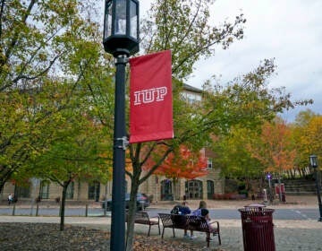 Students sit on a bench on the campus of Indiana University of Pennsylvania in Indiana, Pa