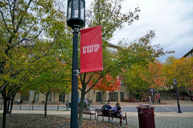 Students sit on a bench on the campus of Indiana University of Pennsylvania in Indiana, Pa