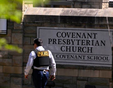 A police officer walks by an entrance to The Covenant School after a shooting in Nashville, Tenn. on Monday, March 27, 2023