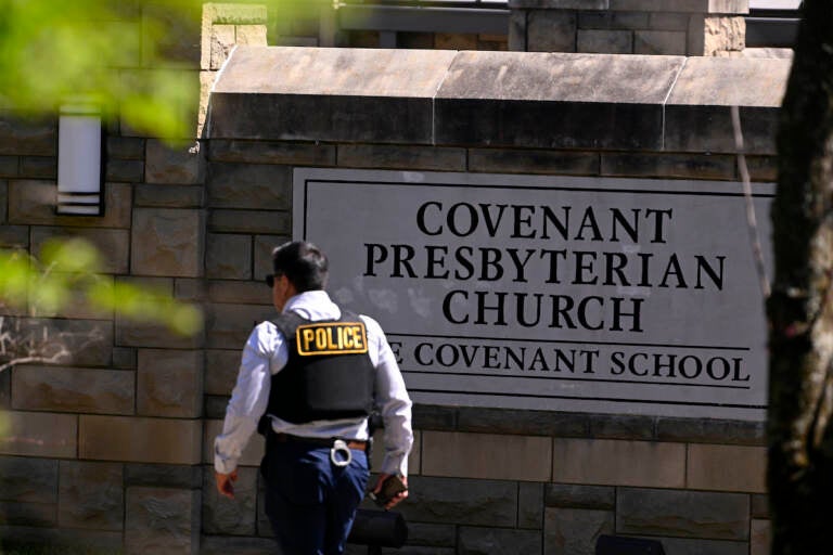 A police officer walks by an entrance to The Covenant School after a shooting in Nashville, Tenn. on Monday, March 27, 2023
