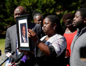 Caroline Ouko, mother of Irvo Otieno, holds a portrait of her son with attorney Ben Crump, left, and her older son, Leon Ochieng at the Dinwiddie Courthouse in Dinwiddie, Va., on Thursday, March 16, 2023. She said Otieno, who died in a state mental hospital March 6, was “brilliant and creative and bright.”  (Daniel Sangjib Min/Richmond Times-Dispatch via AP)