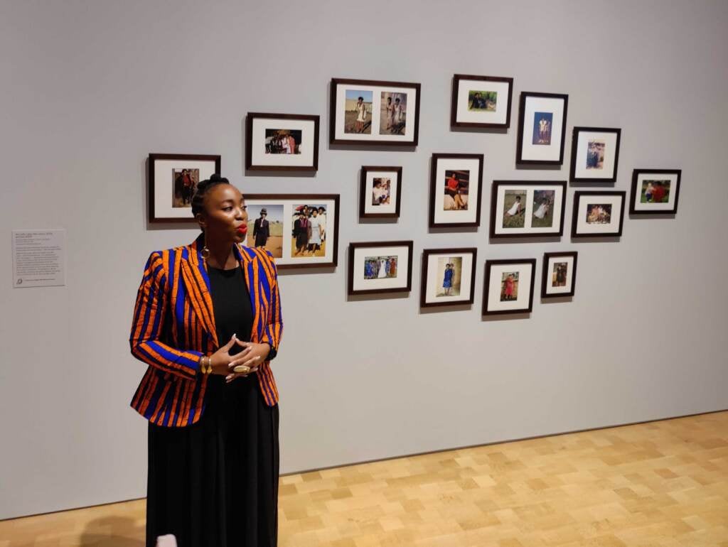 Lebohang Kganye stands in front of a series of snapshots of her mother, in which the artist has inserted herself dressed in the same clothes