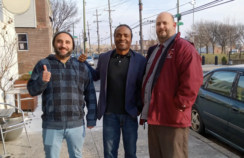 Three men standing on the sidewalk