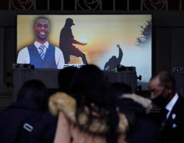 Mourners are seen in front of a screen displaying a photo of Tyre Nichols.