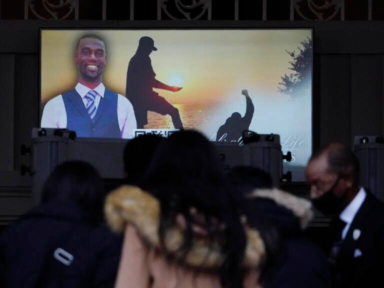 Mourners are seen in front of a screen displaying a photo of Tyre Nichols.