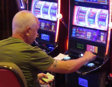 A person has a cigarette in their mouth while playing a slot machine.