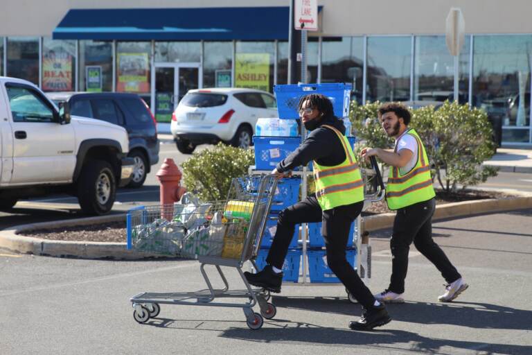 Workers at the Port Richmond Walmart roll more water to the store on Sunday, March 27.