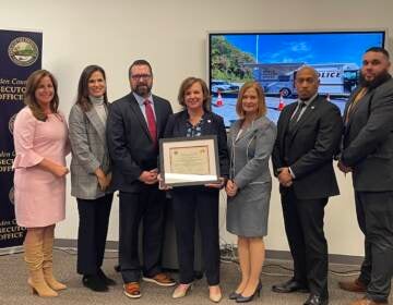 A group of people pose with a framed certificate.