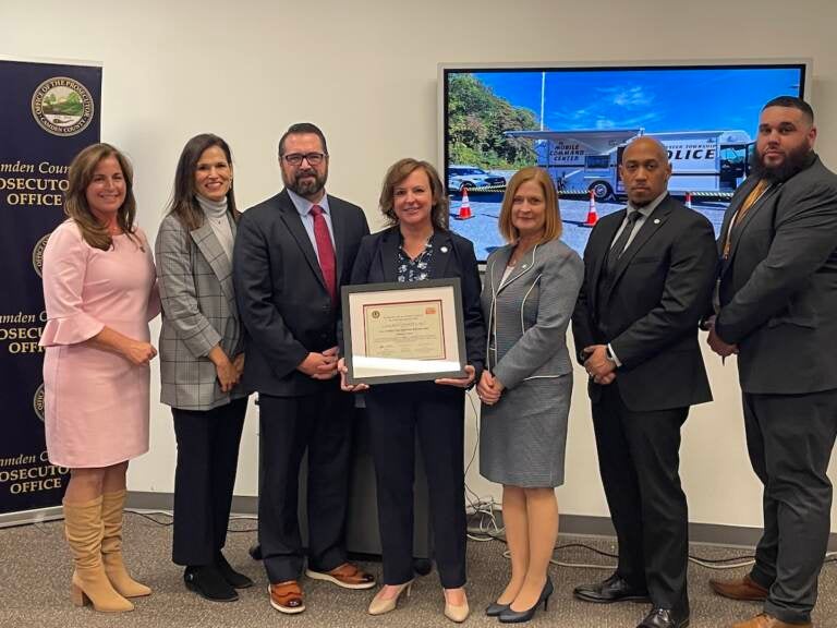 A group of people pose with a framed certificate.