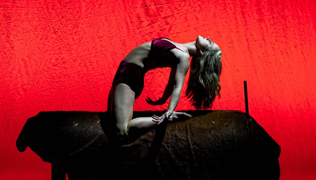 A woman leans backward, silhouetted against a bright red background.