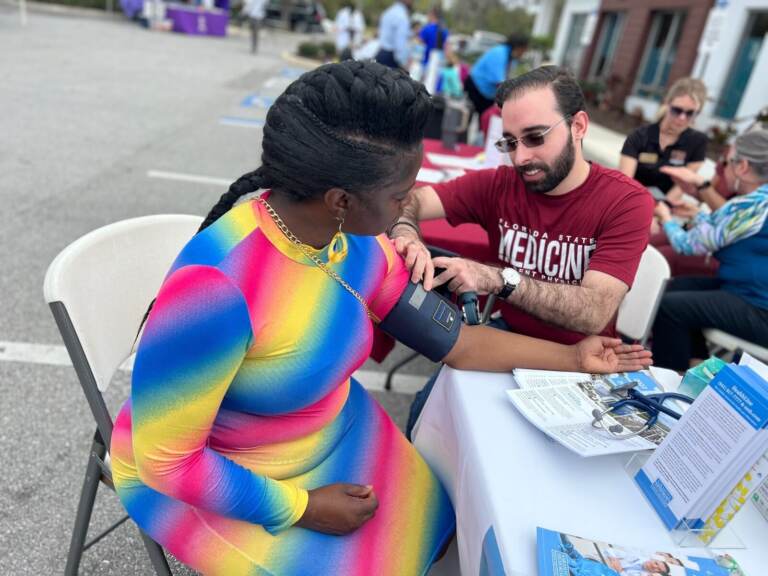 Crystal Clyburn has her blood pressure taken at a table outdoors.