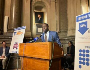 Councilmember Isaiah Thomas speaks at a podium in a room in City Hall with a chart visible to his left.