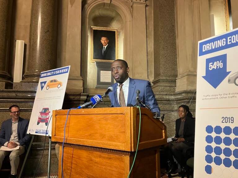 Councilmember Isaiah Thomas speaks at a podium in a room in City Hall with a chart visible to his left.