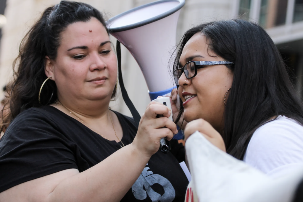 2 women speaking into a megaphone at a rally