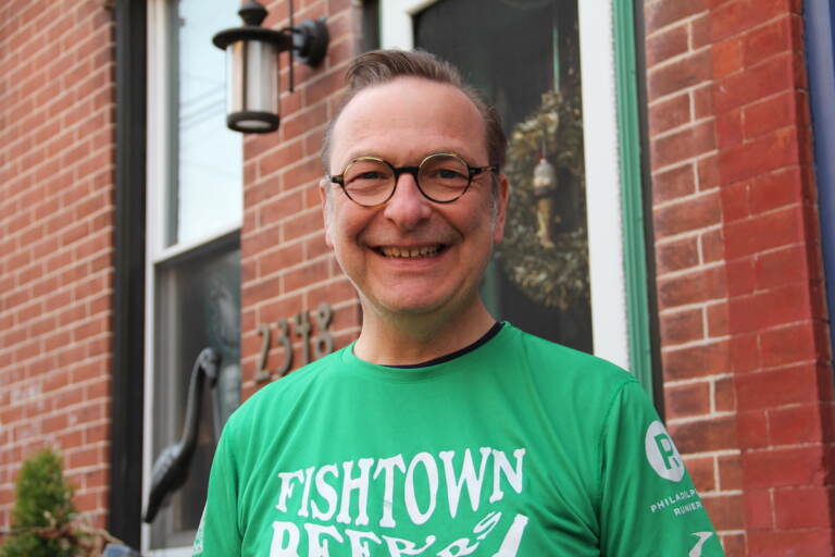 David April smiles, posing outside of a red brick rowhome.