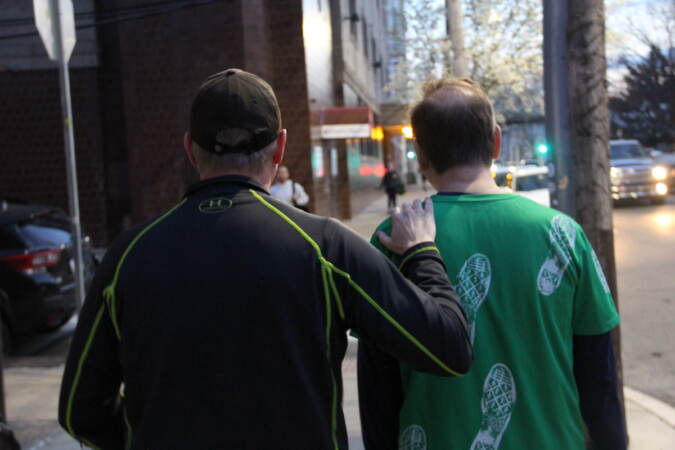 A view from behind of Mark McCowan with his hand on David April's shoulder.