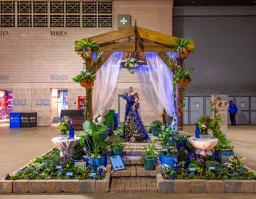 A flower display has a blue gown as its centerpiece.