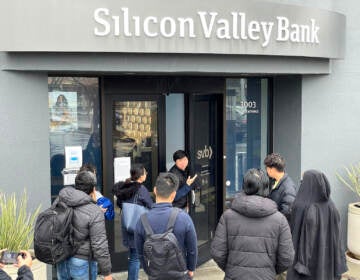 A worker (center) tells people that the Silicon Valley Bank (SVB) headquarters is closed